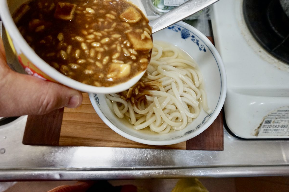 うどんの上に日清カレーメシをかけます。