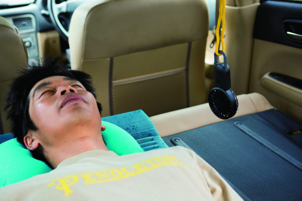 車の中で扇風機に当たりながら寛ぐ人
