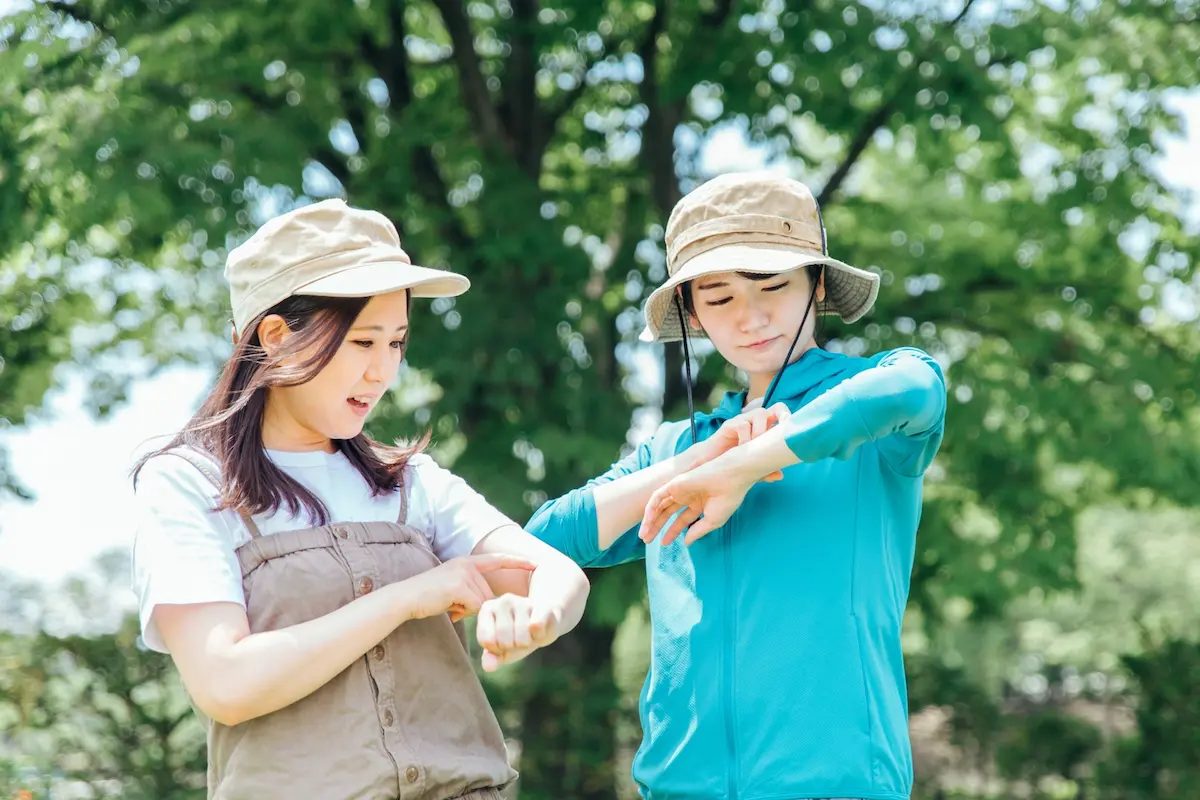 虫に刺されて腕をかく人物2人