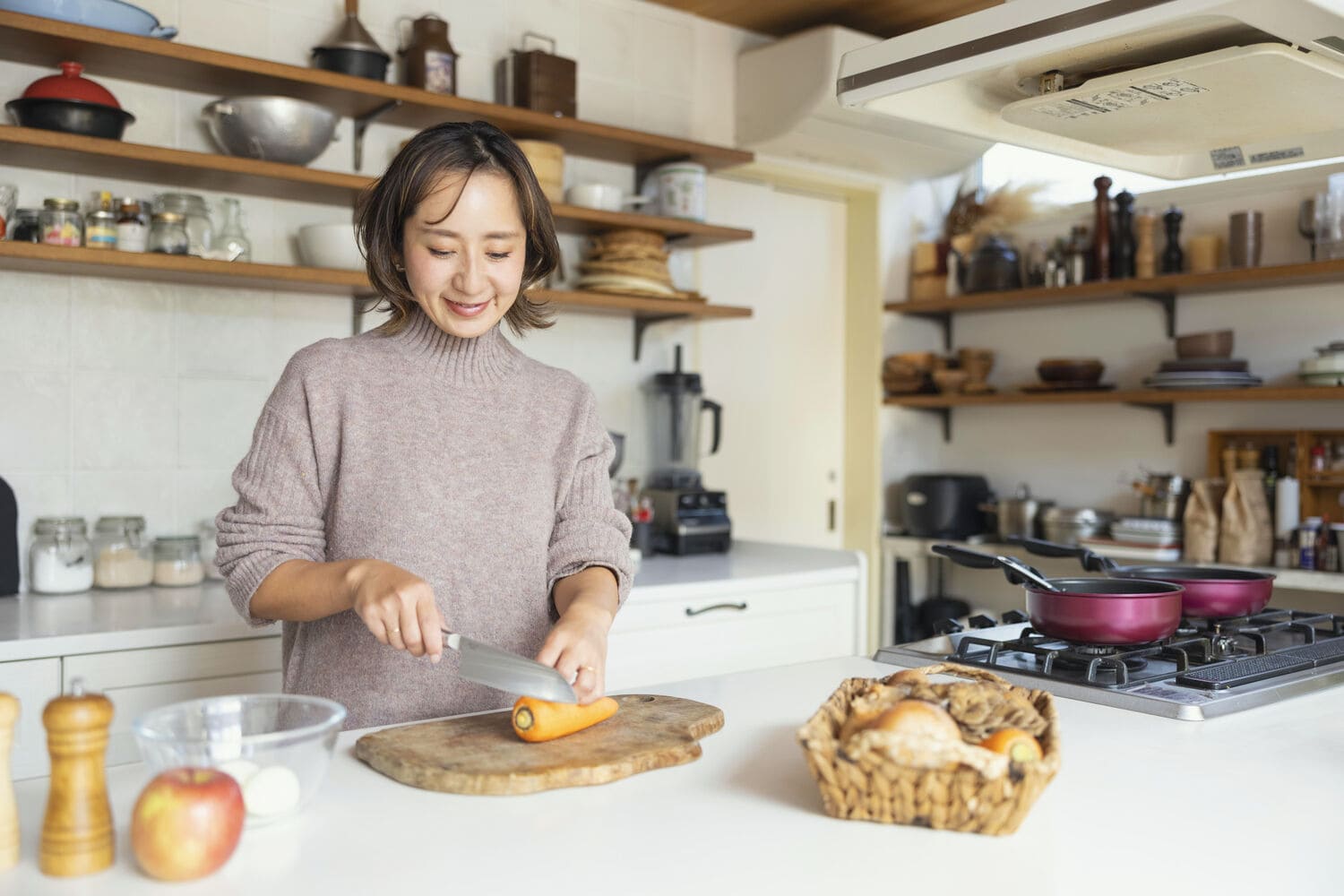 キッチンで人参を切る女性