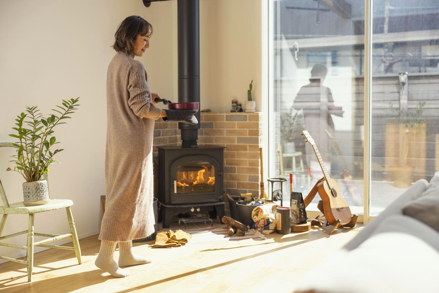 薪ストーブのあるリビングでスープ鍋を運ぶ女性