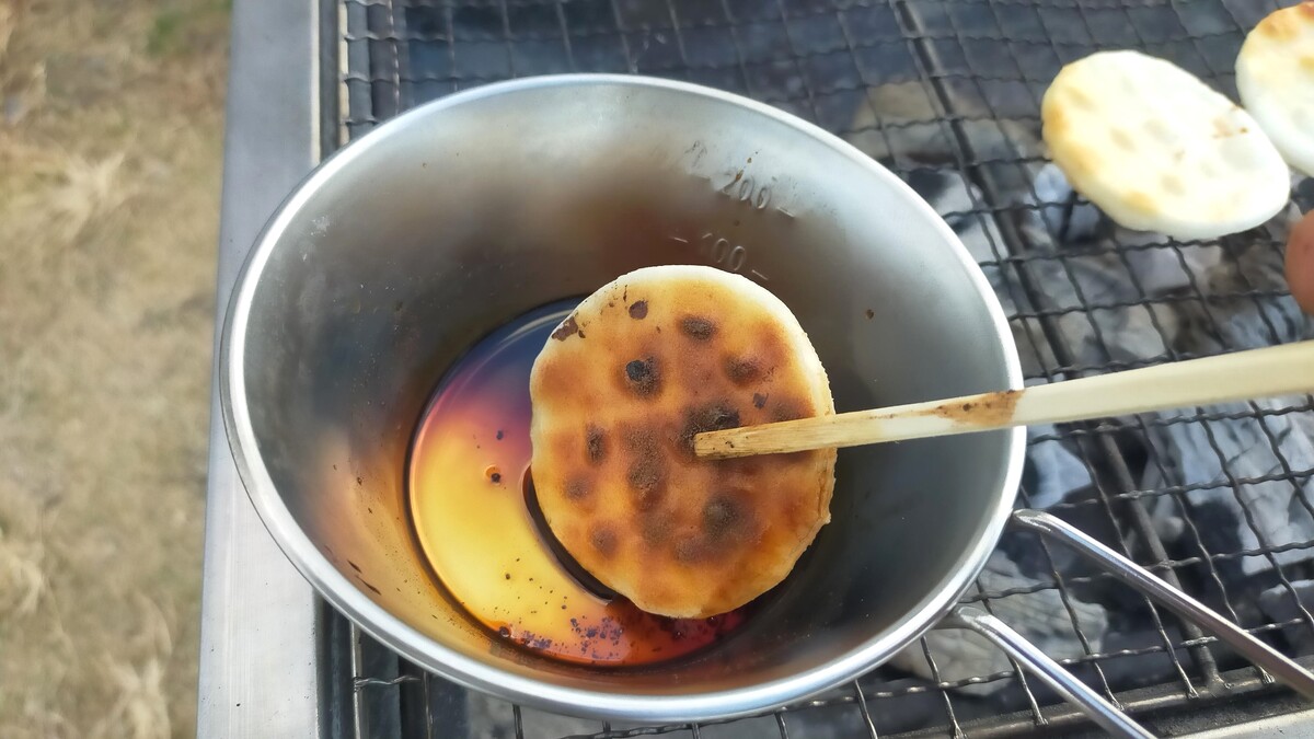 せんべいを醤油に浸している様子。