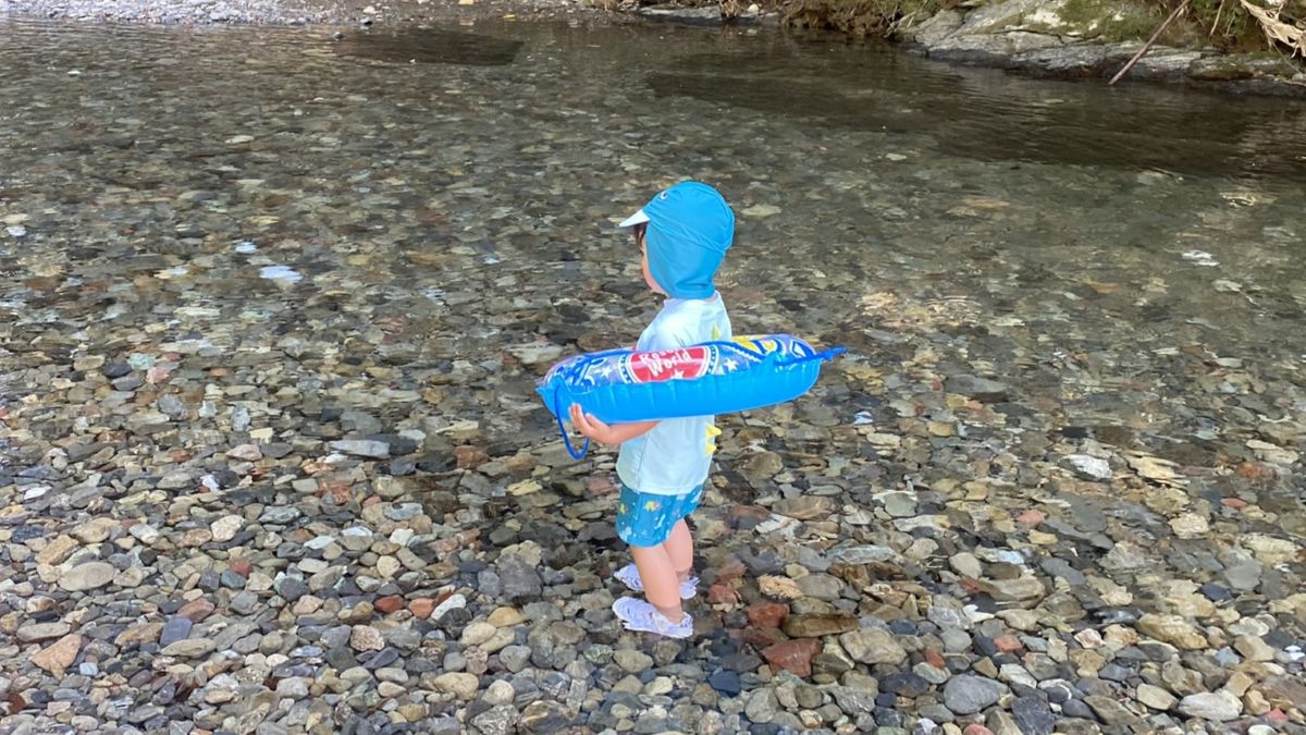 浮き輪を持って川遊びする子ども