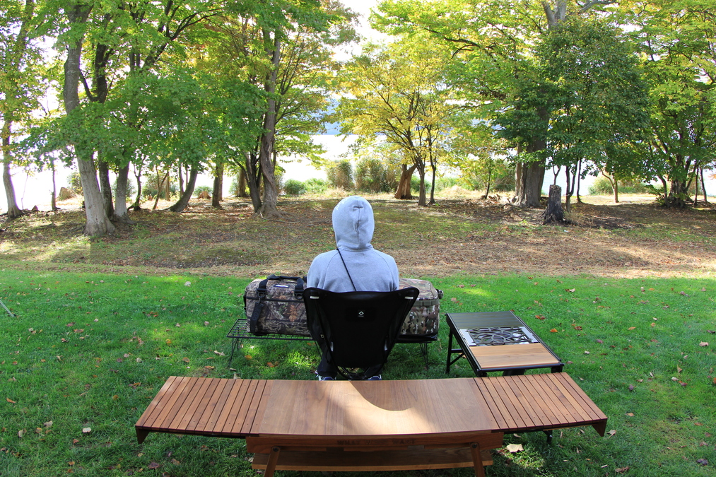 「Helinox タクティカル スウィベル チェア」に座り、後ろを向いて景色を眺める様子。