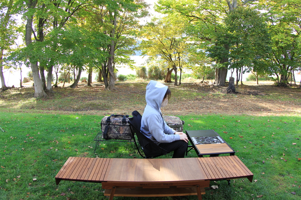 座ったまま左側へ体を向け、テーブル上のギアに手を伸ばす動作をしている様子。