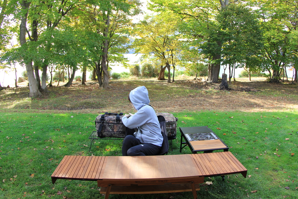 回転しないチェアに座り、後ろの荷物を取ろうとして体をひねっている様子。可動域の狭さが伝わる。