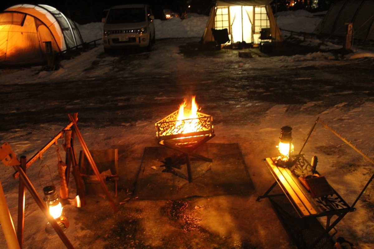 焚き火のそばにオイルランタンを配置した夜のキャンプサイト