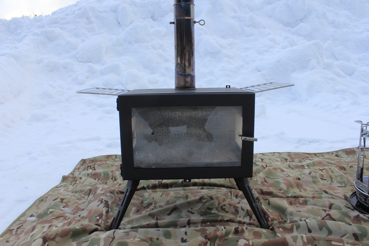 雪原の上に設置されたキャンプ用薪ストーブ