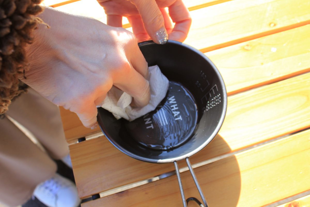 キッチンペーパーでシェラカップ内の油汚れを拭き取っている手元