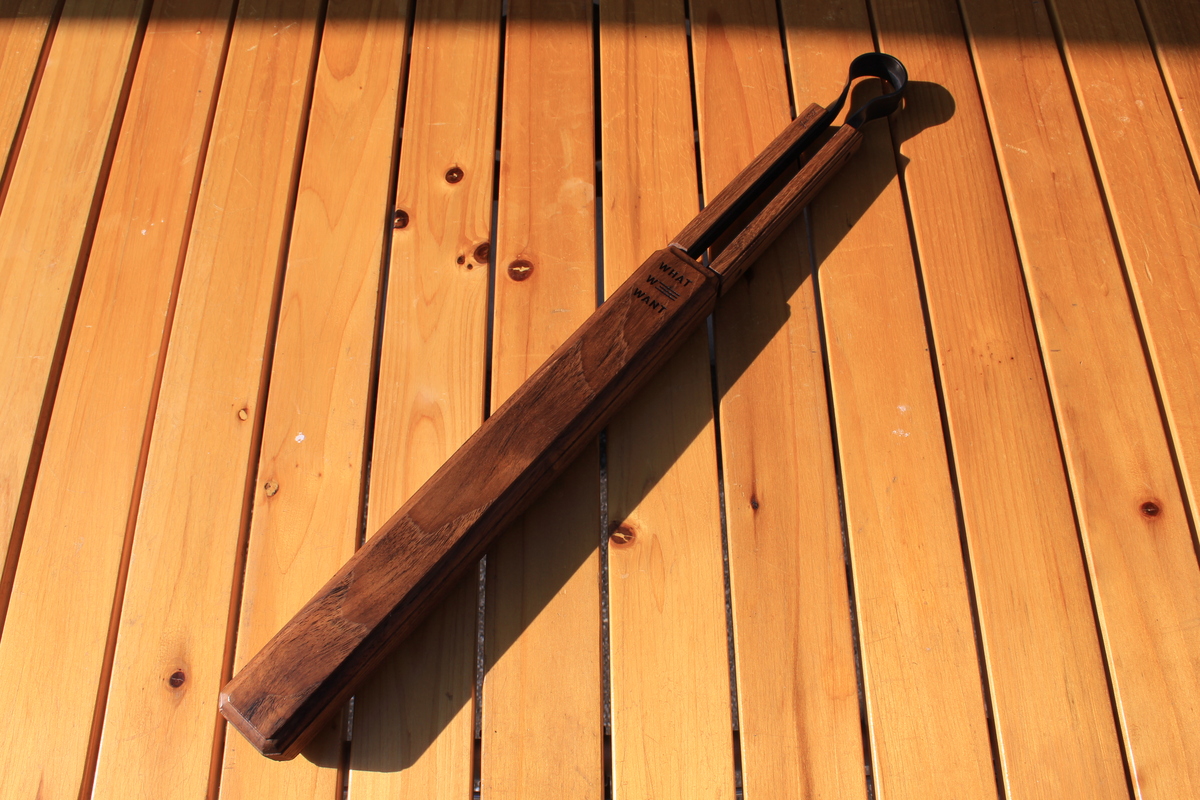 木製ケース「WWW_SAYA」に火ばさみを収納した状態を木のテーブルの上で撮影した写真。