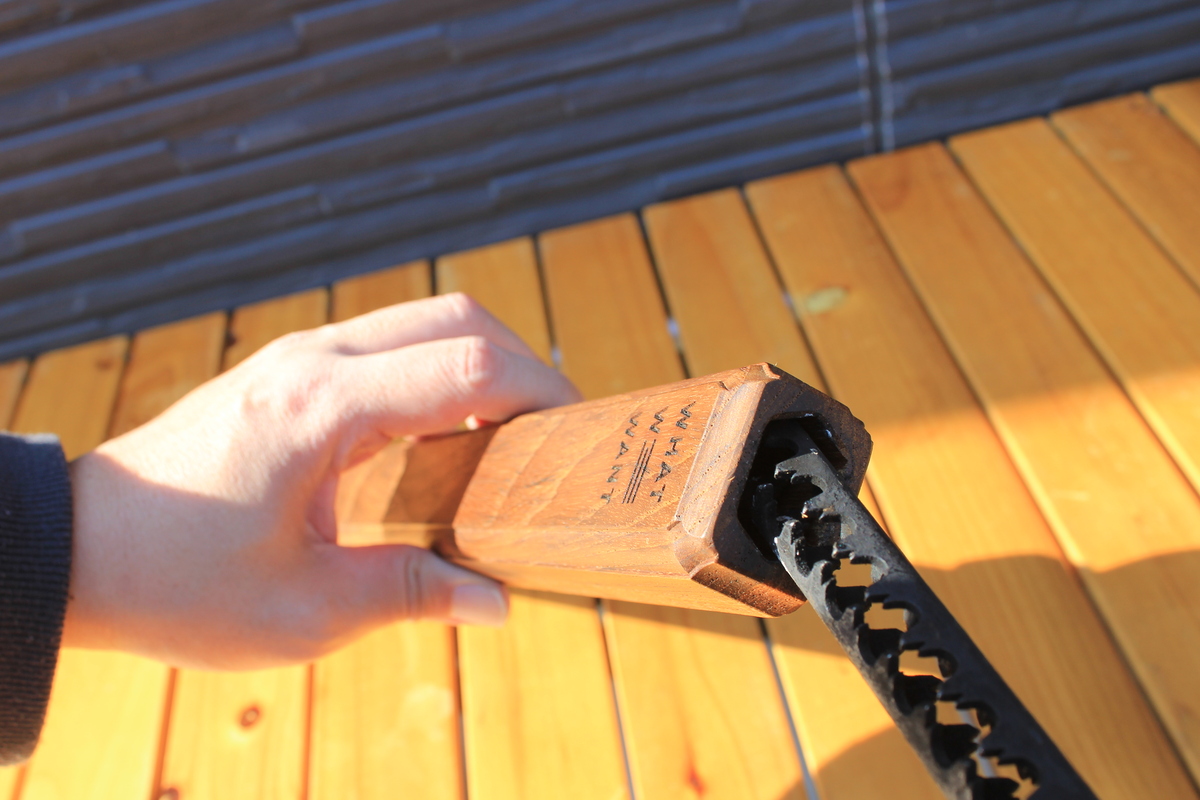 手に持った木製ケース「WWW_SAYA」から火ばさみを出し入れしている様子の写真。