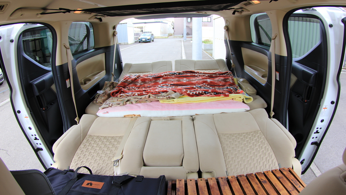 ミニバンの後方スペースに毛布やマットを重ねて車中泊の寝床を作っている車内