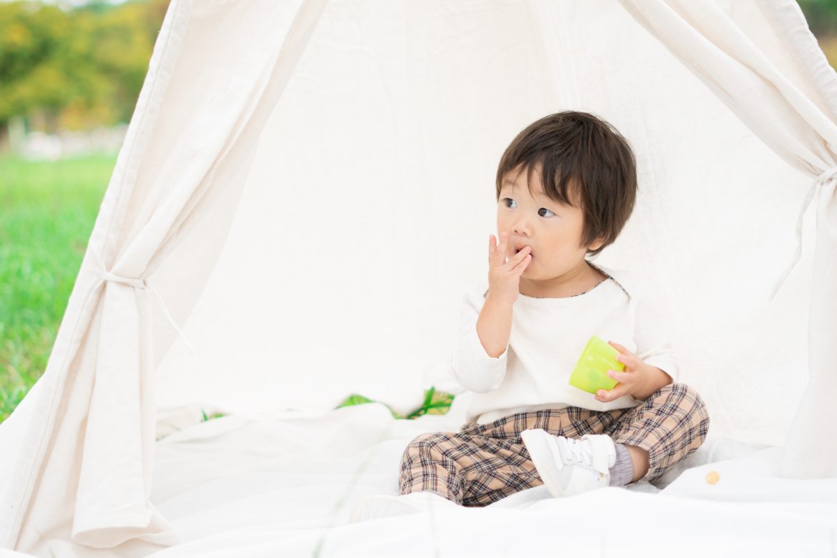 テントでおやつを食べる子供