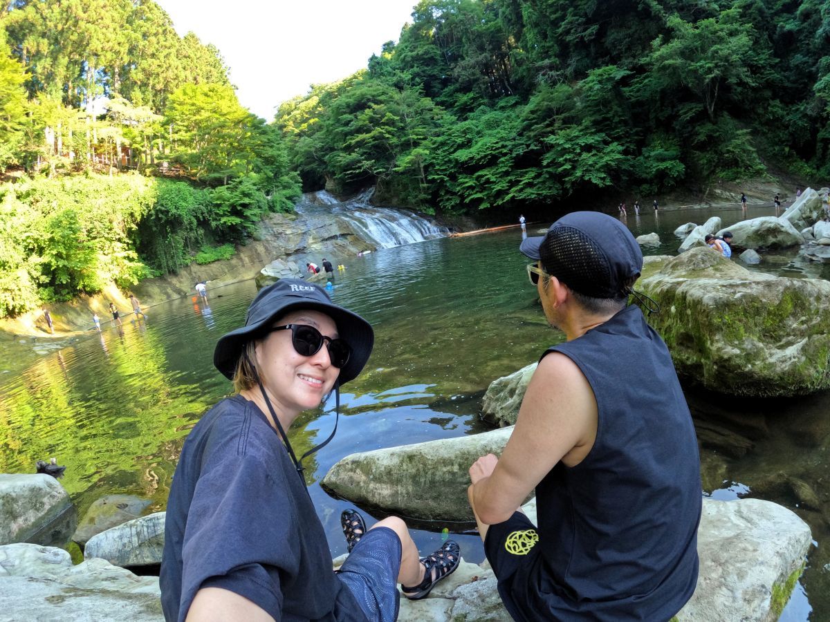 川のそばに座る筆者夫婦
