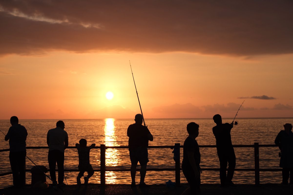 夕日と釣りをする人