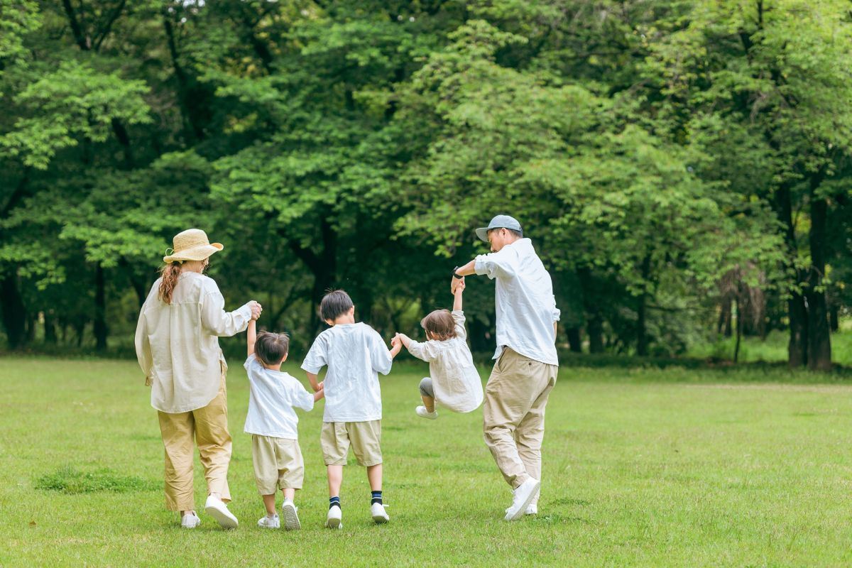 公園を手を繋いで歩く家族の後ろ姿