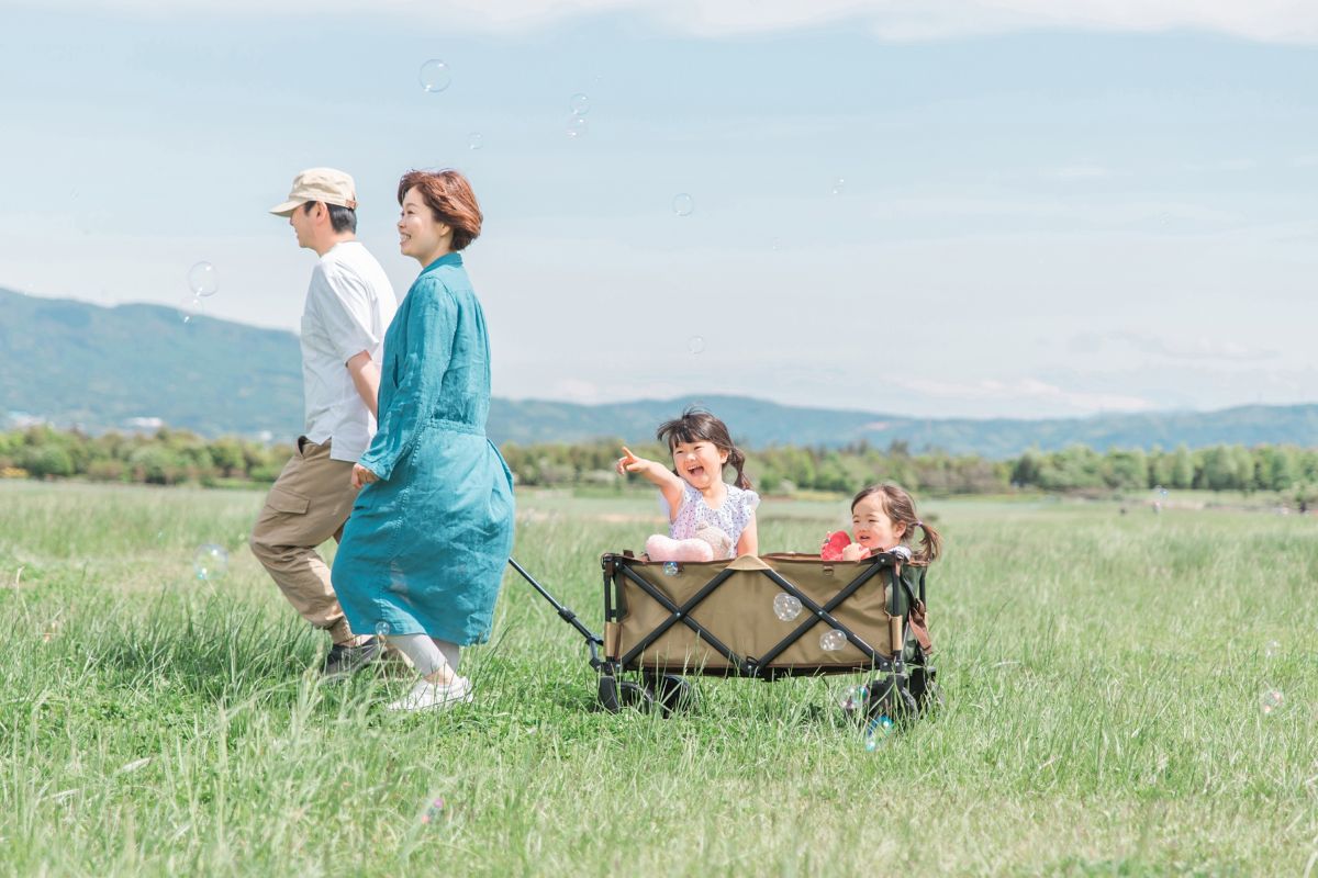 公園をキャリーカートで歩く家族